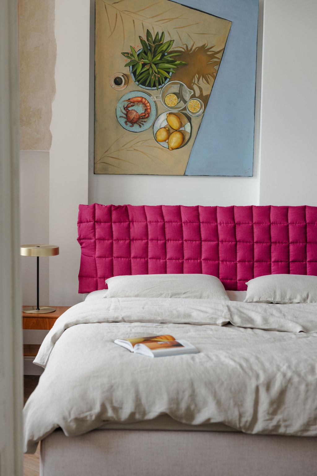 Bedroom with a pink headboard and a painting on the wall.