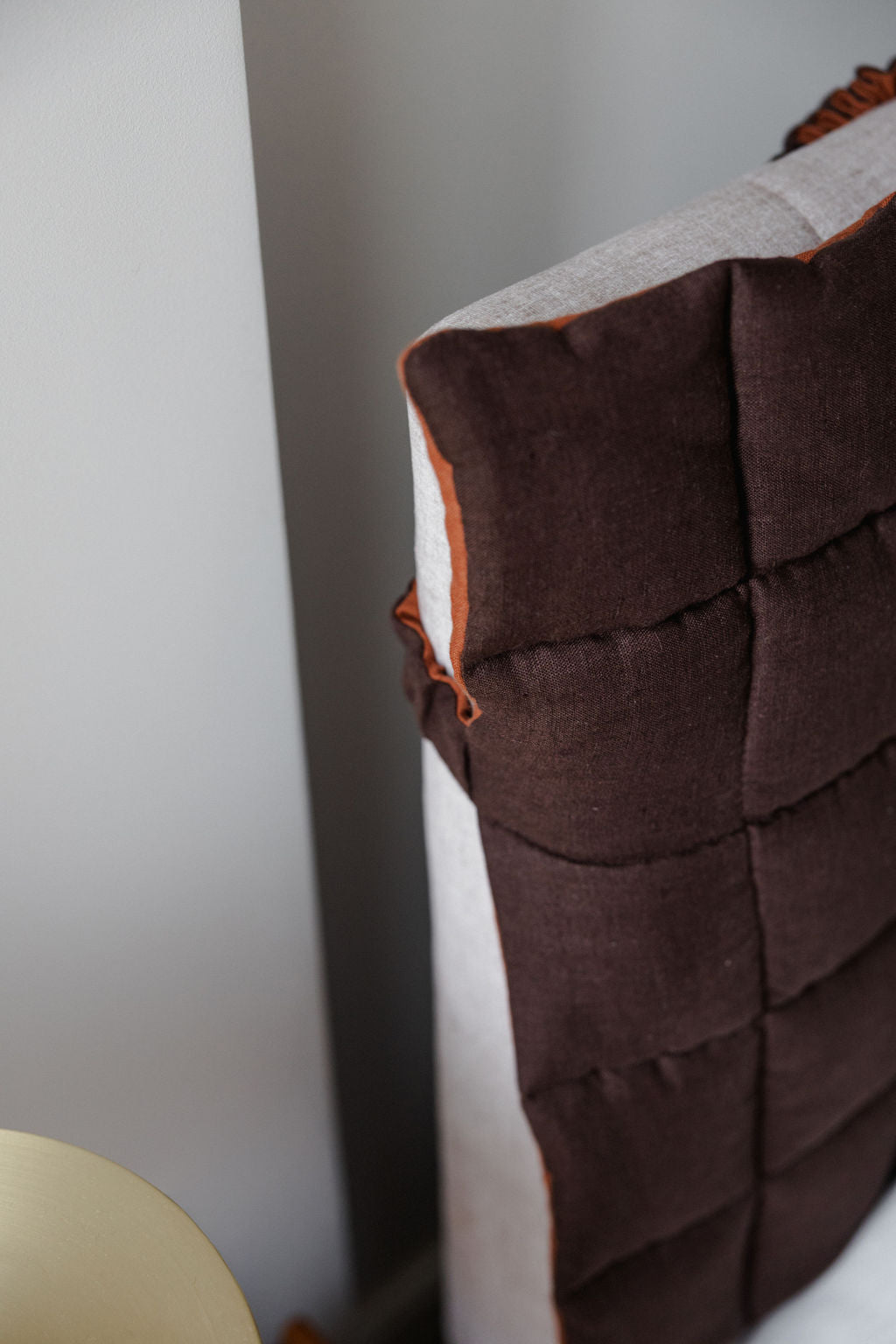 Close-up of a brown textured headboard against a neutral wall.