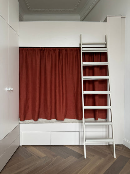 Bunk bed with rust linen curtains and a white ladder in a room with wooden flooring.

