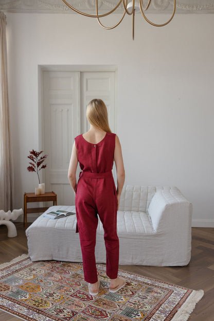 Woman in a red jumpsuit standing in a living room with a white sofa and decorative rug.
