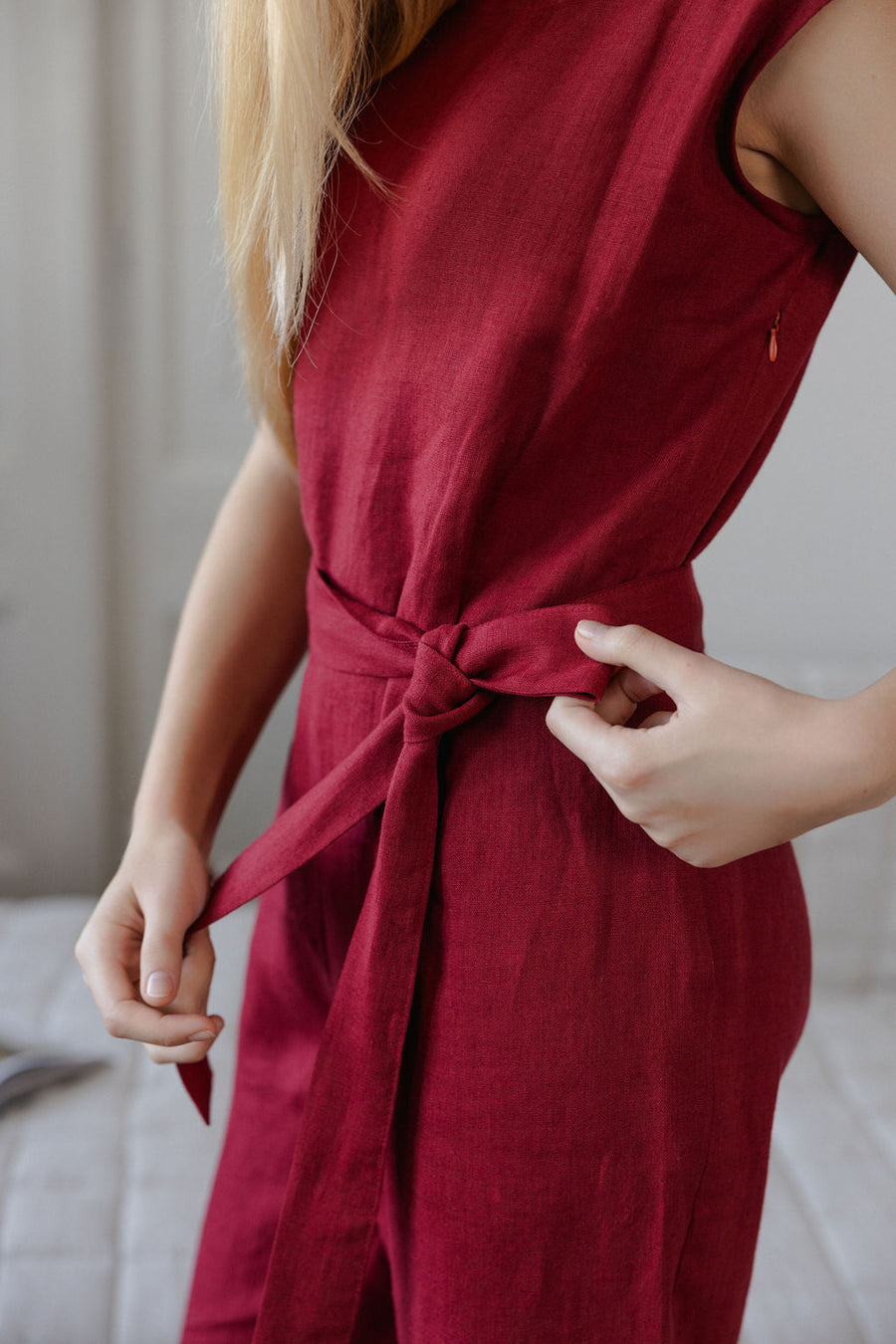 Red dress with a tie waist worn by a person, blurred background