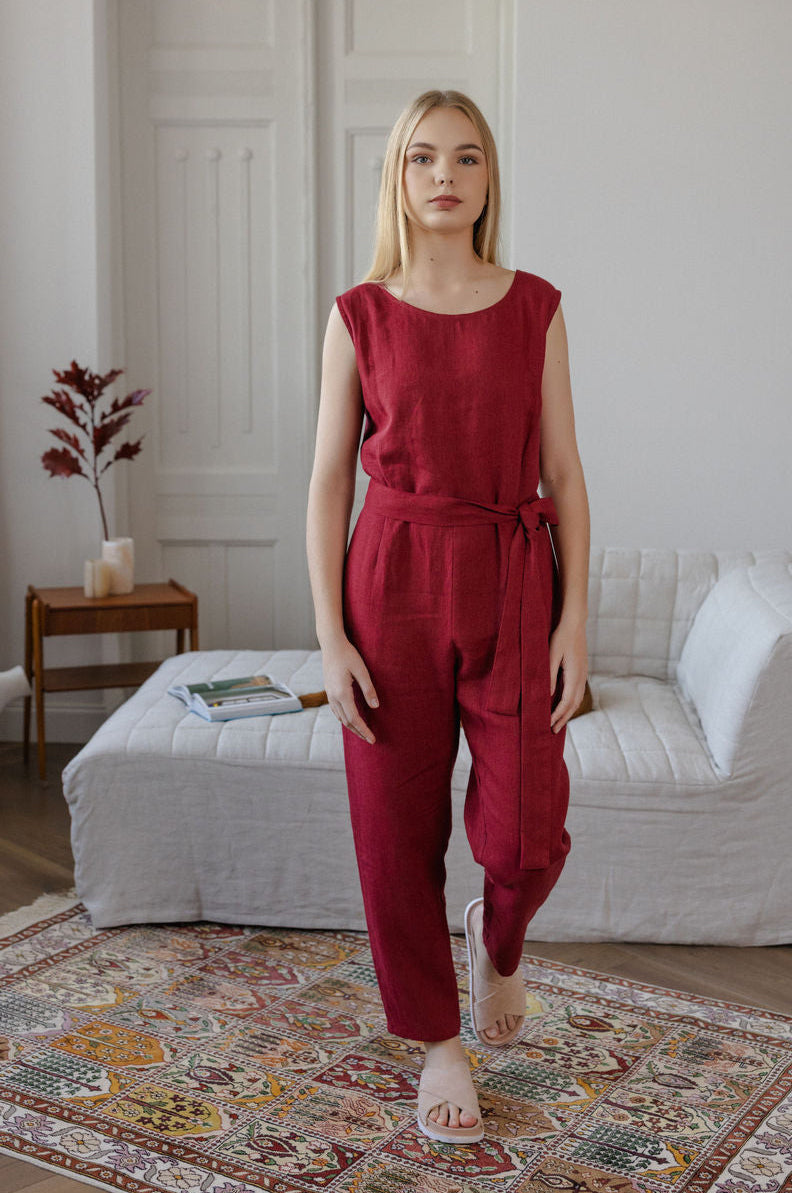 Woman wearing a red jumpsuit standing in a living room.