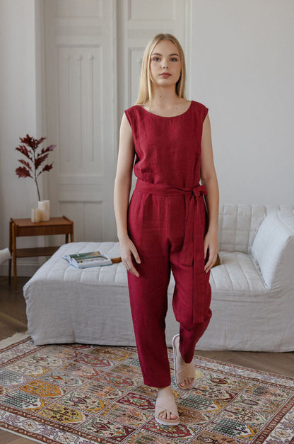 Woman wearing a red jumpsuit standing in a living room.