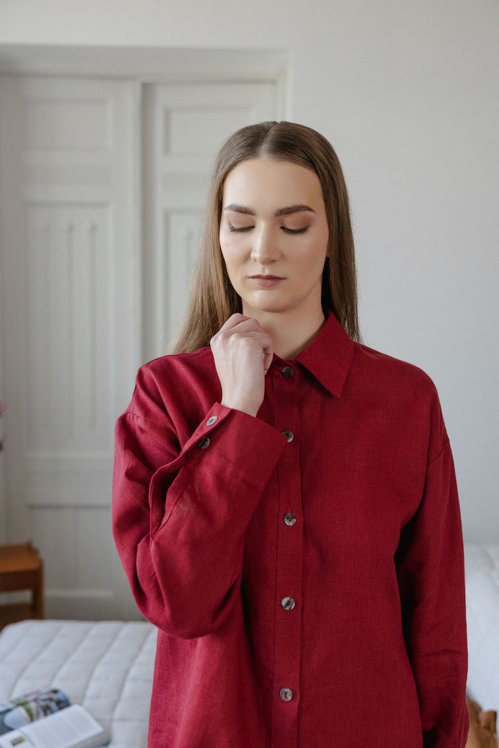 Woman wearing a red shirt in a room with white walls and furniture.