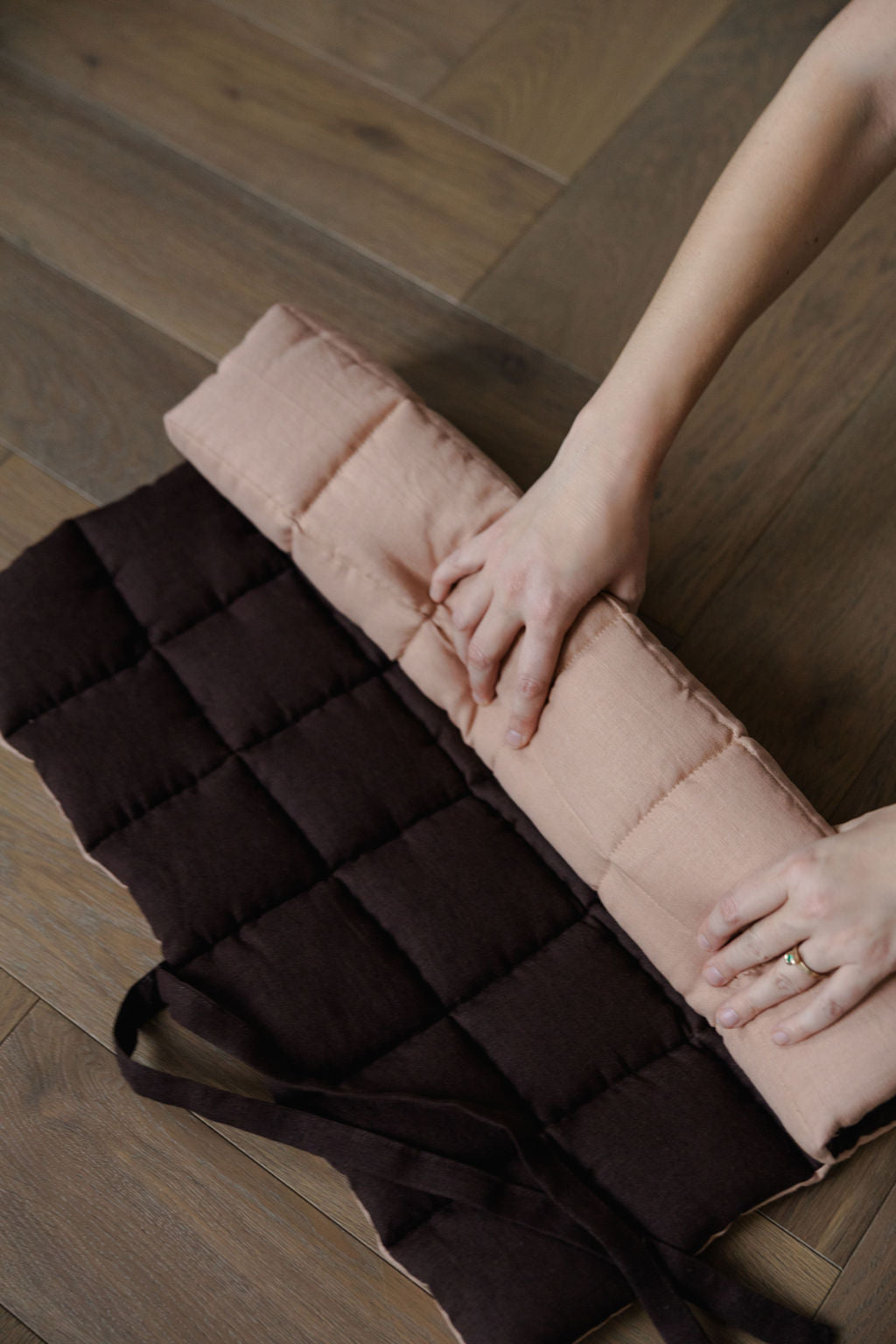 Person holding a quilted mat on a wooden floor